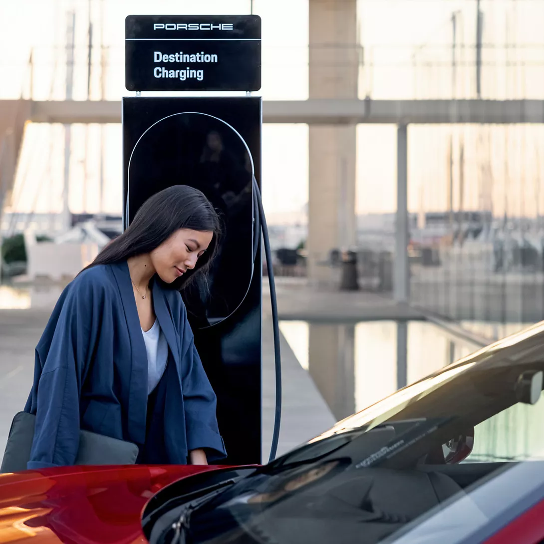 Woman in front of Porsche Charging the car at porsche electric power station