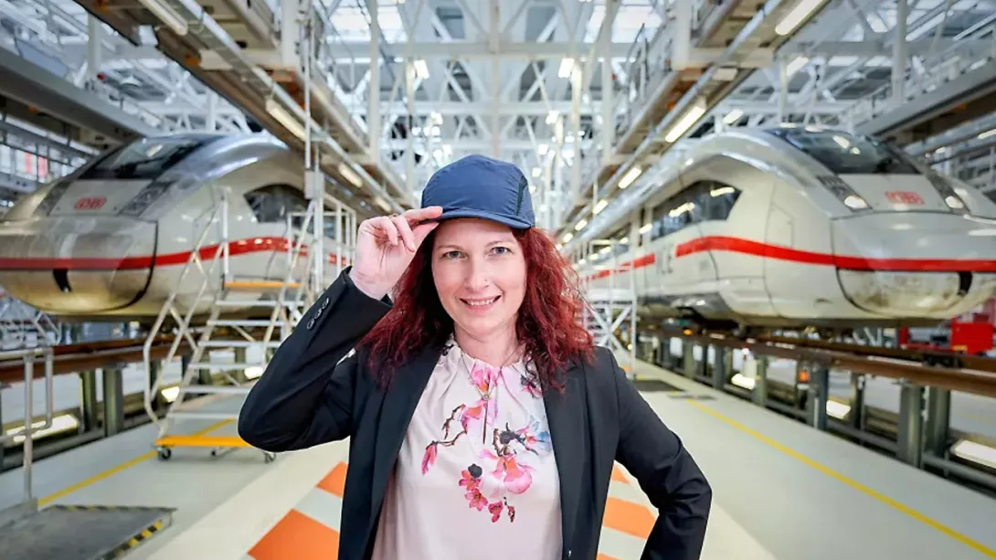 Woman standing in a factory hall in front of two Deutsche Bahn ICE trains