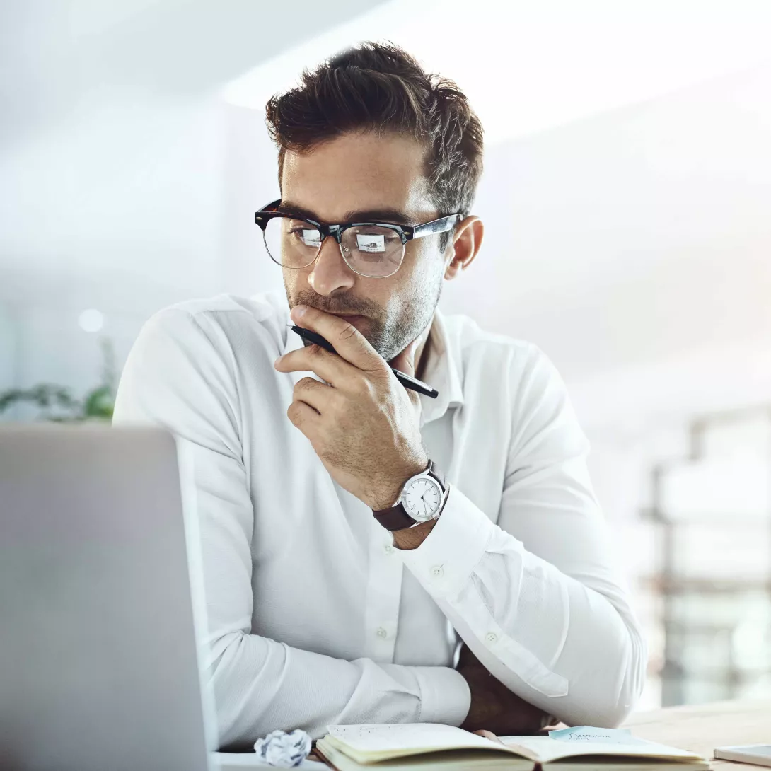 Mann am arbeiten schaut auf seinen Laptop und überlegt