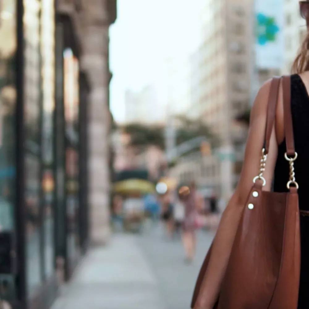 Woman's shoulder with a bag at the edge of the picture in a shopping street