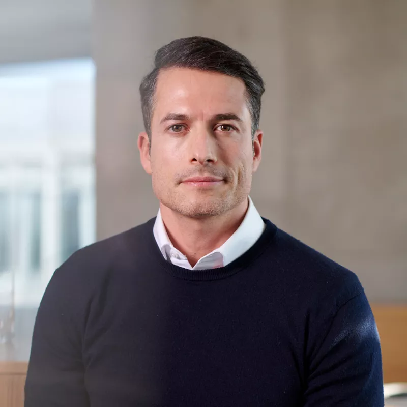 Portrait of a dark-haired consultant with white shirt and blue jumper