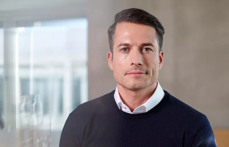 Portrait of a dark-haired adviser with white shirt and blue jumper
