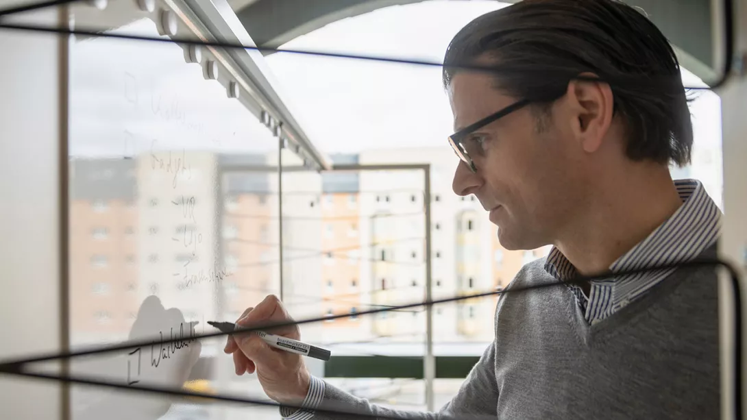 Man writing something on a whiteboard in an office