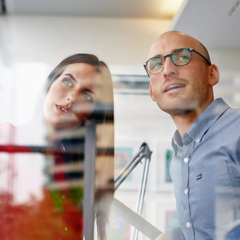 A woman and a man stand together and look at something together