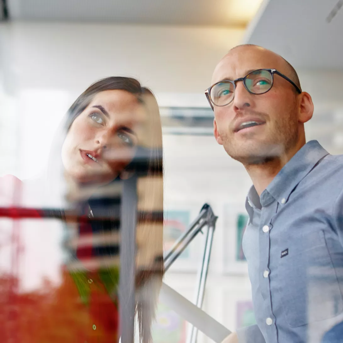 A woman and a man stand together and look at something together