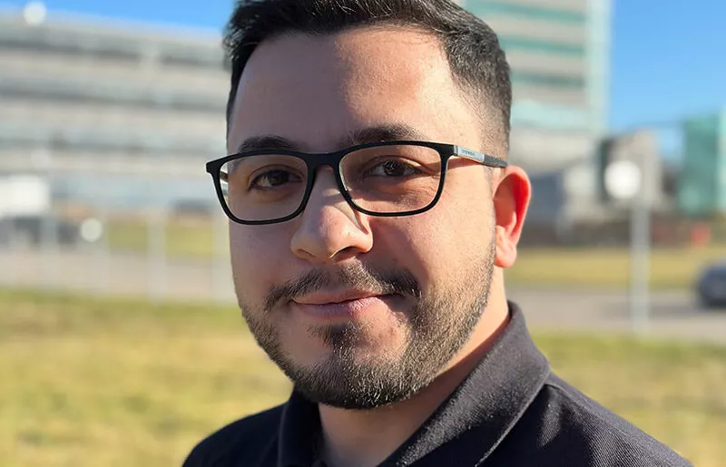 Young man looks into the camera in front of skyscrapers in the background