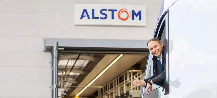 ALSTOM logo shown with man in the front pointing a thumbs-up symbol