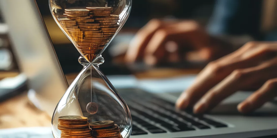 Sanduhr mit Geld und Laptop Arbeitszeit